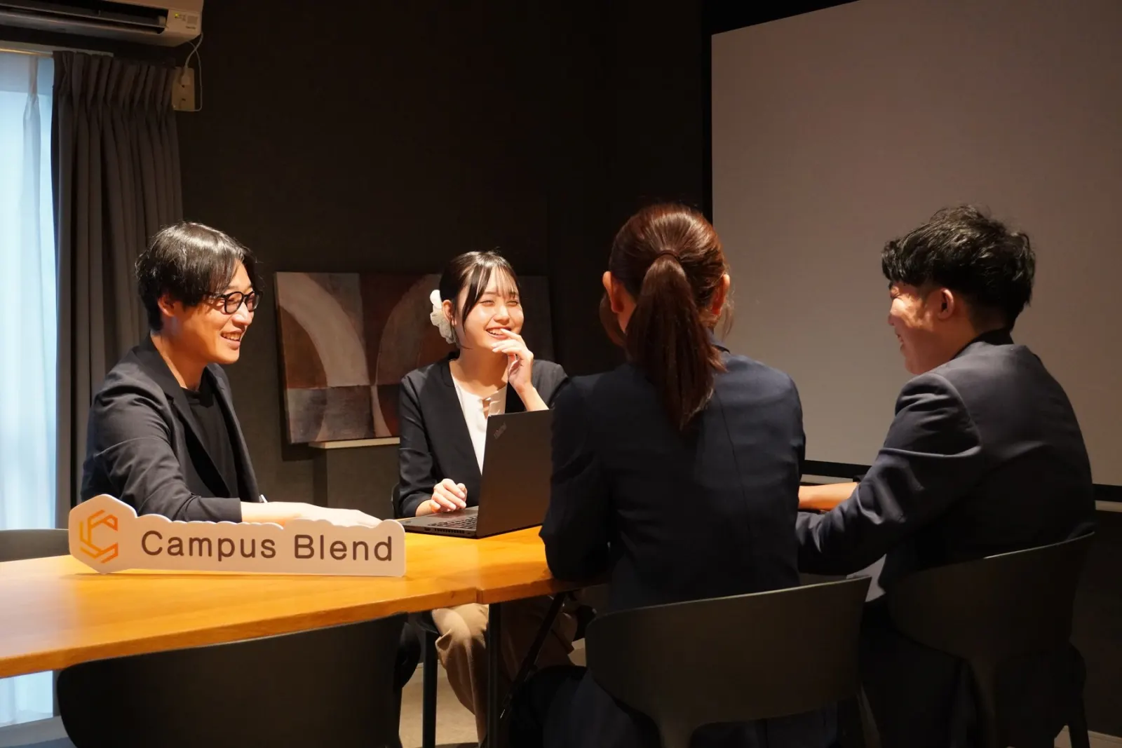 Campus Blendのロゴを置いたテーブルで打ち合わせをするメンバー